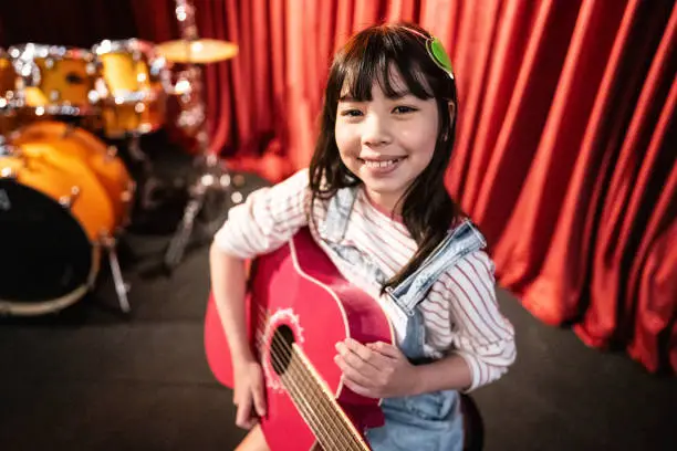 child with a smile holding a guitar