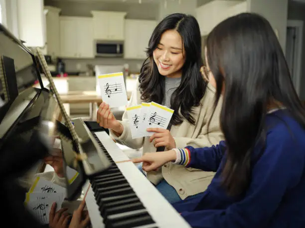 piano teacher and student sitting
     at a piano